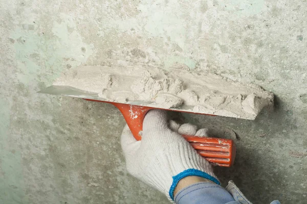 Conceito de construção e renovação. Mão de homem em luva com espátula durante o reparo de parede . — Fotografia de Stock