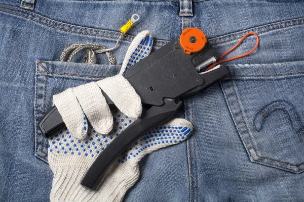 Strumento elettrico, cavo e guanto di lavoro sullo sfondo di jeans.. Concetto di energia . — Foto Stock