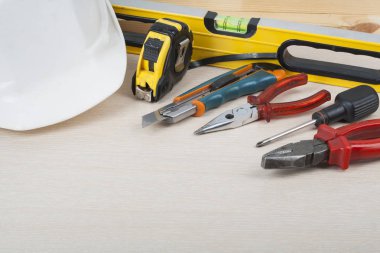 İnşaat araçları ve ahşap arka plan üzerinde beyaz kask. Metin için yer kopyalayın.