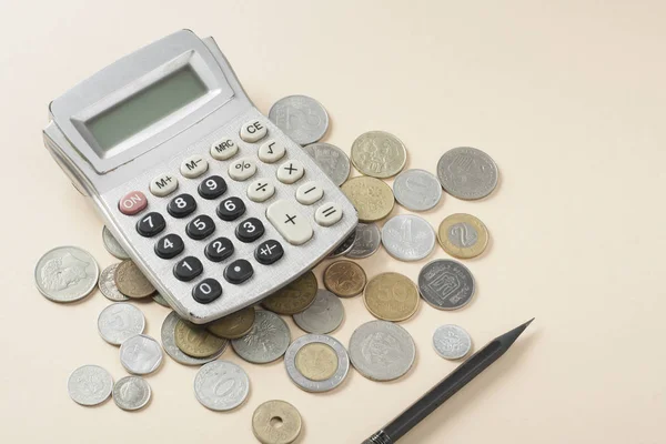 Strona główna oszczędności, koncepcja budżetu. Kalkulator, pióra i monety na beżowym tle. — Zdjęcie stockowe