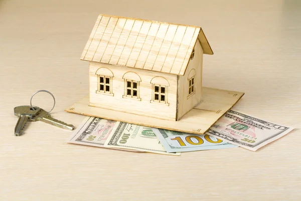 Ev tasarruf, bütçe kavramı. Model ev, anahtarları ve para ahşap ofis masaları.