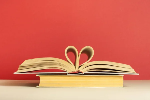 Book pages folded in heart shape on red background. Copy space for text. Stock Photo