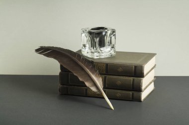 Kitaplar ve InkWell ahşap masa üzerinde tüy kalemle yığını. Ücretsiz kopya alanı.
