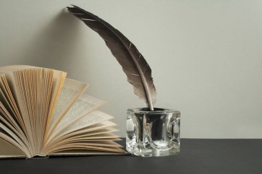Açık kitap ve tüy kalemle InkWell ahşap masa üzerinde. Ücretsiz kopya alanı.