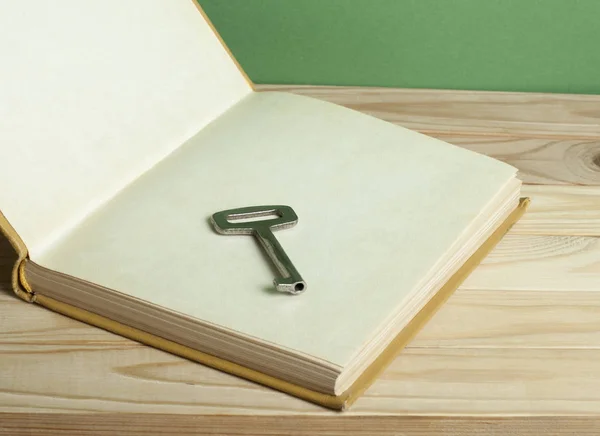 Schlüssel zum Wissenskonzept. Buch mit Schlüssel auf Holzgrund aufschlagen. — Stockfoto