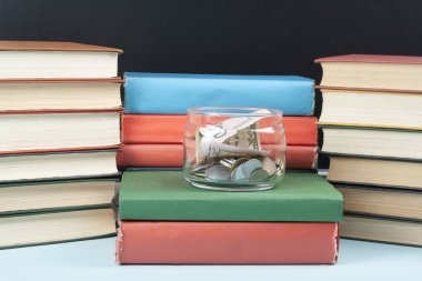 Para cam ve ahşap masa üzerinde kitap yığını. Kaydetme, mali ve eğitim kavramı.