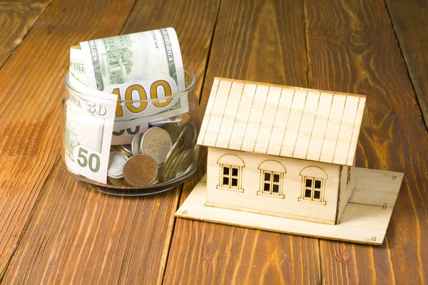 Home savings, budget concept. Model house and coins on wooden office desk table.