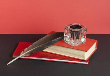 Kitap ve tüy kalemle InkWell kırmızı duvar arka plan üzerinde siyah masada. Ücretsiz kopya alanı. Eğitim kavramı.