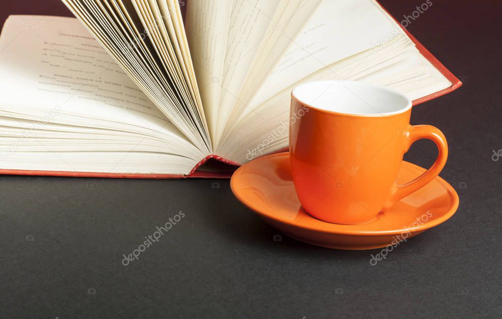 Cup for tea or coffee and open book on black background. Education concept.