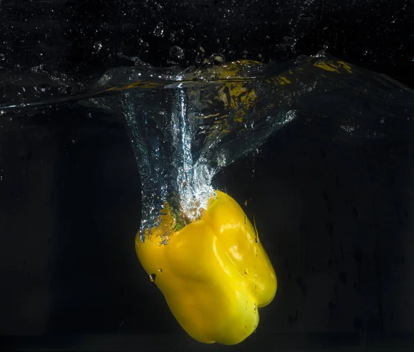 Yellow pepper splashing in the water with bubbles