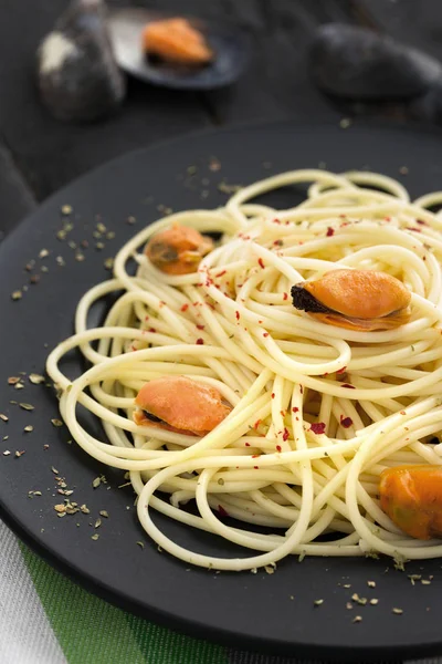 Espaguetis mejillones en plato negro de cerca — Foto de Stock