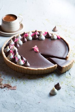 Çikolatalı tart ve pembe çiçeklerle süslenmiş bir tatlı masası.