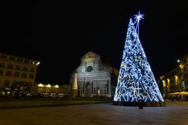 Florence, Aralık 2019: Santa Maria Novella Meydanı 'nda arka planda Bazilika ile aydınlatılmış Noel ağacı. İtalya.