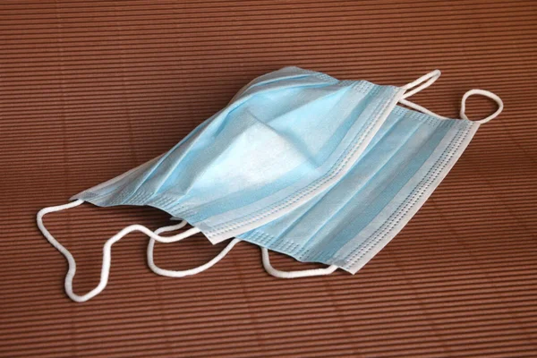Koronavirüse karşı korunmak için antiviral tıbbi maske. Cerrahi koruyucu maske. Kahverengi arka planda tıbbi solunum bandajı var. Virüs ve salgın COVID-19 'un yayılmasının önlenmesi.