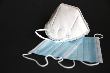 Siyah arka planda koronavirüse karşı korunmak için antiviral tıbbi maskeli beyaz KN95 veya N95 maskesi. Cerrahi koruyucu maske. Virüs ve salgın COVID-19 'un yayılmasının önlenmesi.