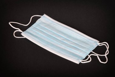 Koronavirüse karşı korunmak için antiviral tıbbi maske. Cerrahi koruyucu maske. Siyah arka planda tıbbi solunum bandajı var. Virüsün yayılmasını önlemek ve salgın COVID-19.