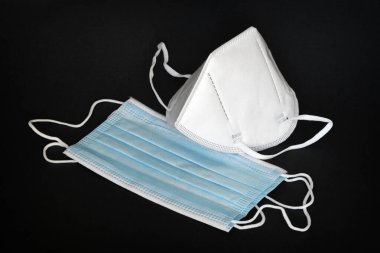 Siyah arka planda koronavirüse karşı korunmak için antiviral tıbbi maskeli beyaz KN95 veya N95 maskesi. Cerrahi koruyucu maske. Virüs ve salgın COVID-19 'un yayılmasının önlenmesi.