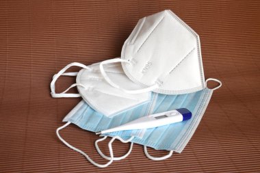 Beyaz tıbbi maskenin ayrıntıları FFP2 KN95 ile koronavirüsten korunmak için antiviral tıbbi maske ve termometre. Virüslerin ve salgın COVID-19 'un önlenmesi.