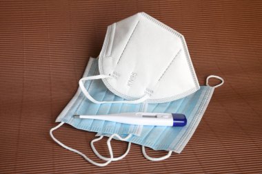Beyaz tıbbi maskenin ayrıntıları FFP2 KN95 ile koronavirüsten korunmak için antiviral tıbbi maske ve termometre. Virüslerin ve salgın COVID-19 'un önlenmesi.