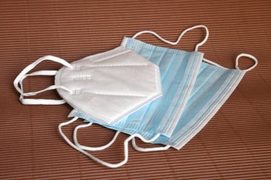 Kahverengi arka planda Coronavirus 'a karşı korunmak için antiviral tıbbi maskeli beyaz KN95 veya N95 maskesi. Cerrahi koruyucu maske. Virüs ve salgın COVID-19 'un yayılmasının önlenmesi.