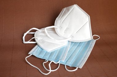 Kahverengi arka planda Coronavirus 'a karşı korunmak için antiviral tıbbi maskeli beyaz KN95 veya N95 maskesi. Cerrahi koruyucu maske. Virüs ve salgın COVID-19 'un yayılmasının önlenmesi.