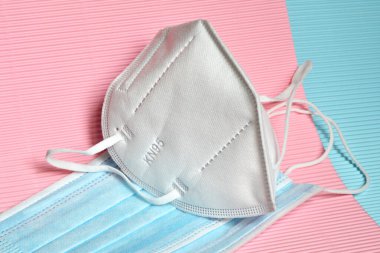 Renkli arka planda koronavirüse karşı korunmak için antiviral tıbbi maskeli beyaz KN95 veya FFP2 maskesi. Virüsün yayılmasını önlemek ve salgın COVID-19.