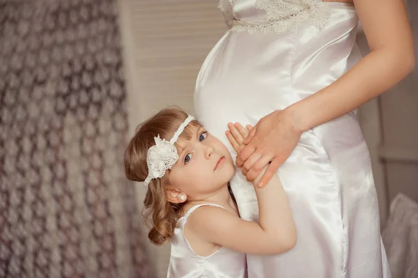 Maman et fille en tenues blanches identiques. Femme enceinte . — Photo