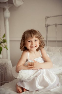 Küçük kız sabah uyandım ve ile yatakta oturur 