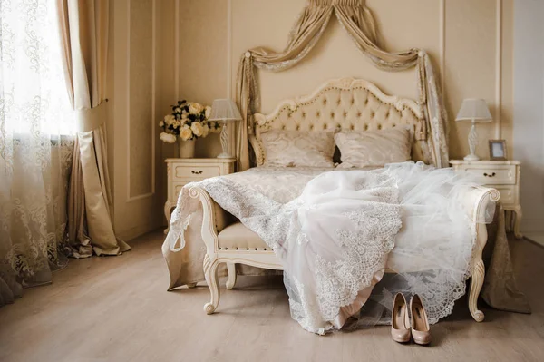 Das Hochzeitskleid liegt im Zimmer auf dem Bett. Beige Hochzeitsschuhe — Stockfoto