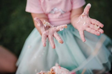 Kız ellerini krema ile lekeli. Doğum günü kızı. Cakesmash.