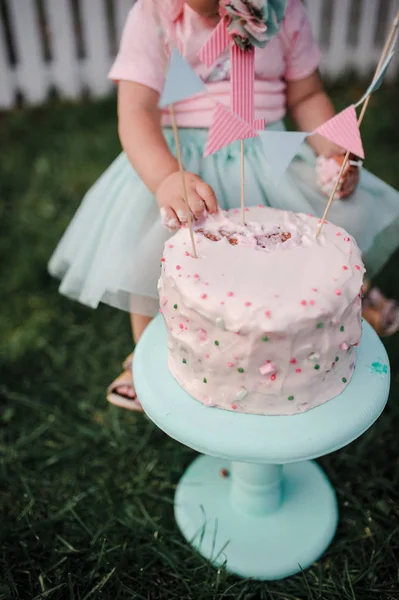 这个女孩的第一个生日一个生日蛋糕。女孩的手 t — 图库照片