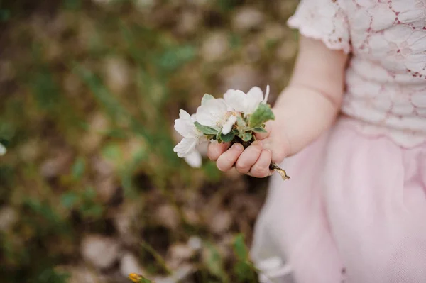 Маленька дівчинка сидить на траві і тримає в руках квіти — стокове фото