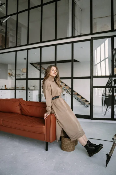 Chica rubia con el pelo largo en un vestido de punto marrón en un apartamento con estilo — Foto de Stock