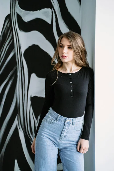 Retrato de una hermosa chica con el pelo largo rubio en una camiseta negra y jeans en el fondo de un patrón de cebra — Foto de Stock