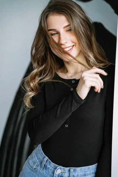 Retrato de una hermosa chica con el pelo largo rubio en una camiseta negra y jeans — Foto de Stock