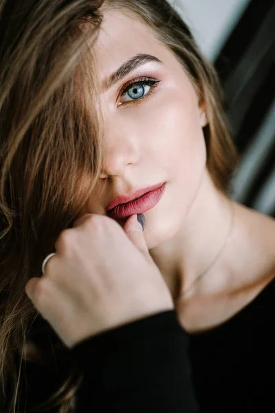 Portrait d'une belle fille aux cheveux longs marron clair en t-shirt noir et jean dans les escaliers de la maison. Beaux yeux bleus — Photo