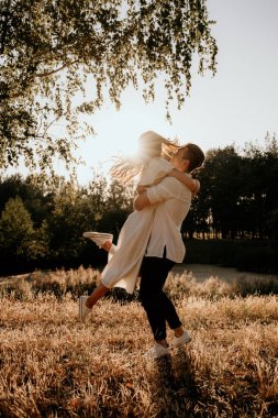 Sevgi dolu çiftler yazın gün batımında doğada yürürler ve koşarlar. Şapkalı ve açık renk elbiseli esmer kız. Aşk hikayesi..