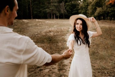 Genç çift yaz çayırlarında gün batımında yürüyor.