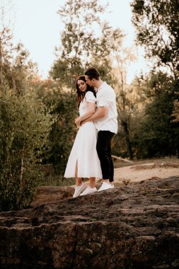 Genç çift yaz çayırlarında gün batımında yürüyor.