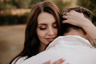 Sevgili çift yazın gün batımında sarılıyor. Açık renk elbiseli esmer kız. Aşk hikayesi..