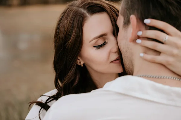 Milující pár objímající se při západu slunce v létě. Bruneta v lehkých šatech. Milostný příběh. — Stock fotografie