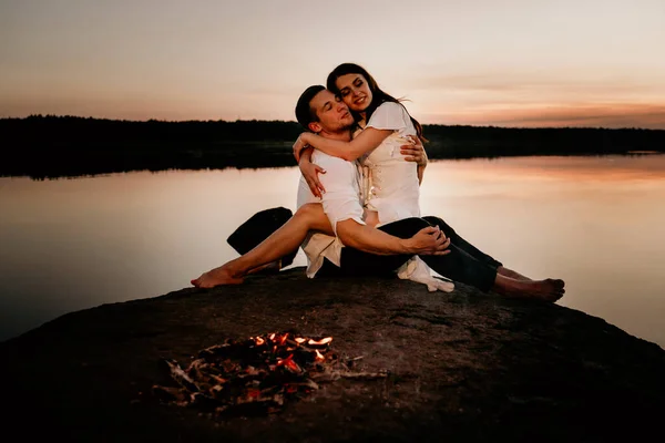 一对年轻夫妇在日落海岸的火边拥抱和亲吻 浪漫的爱情故事 — 图库照片