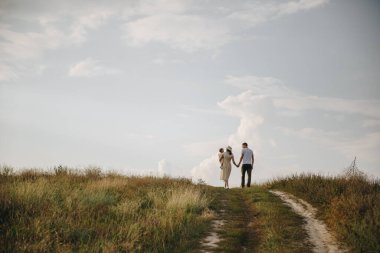 Aile, anne, baba, kız tarlada bir tepede yürüyorlar. Anne ve kızı aynı sarı elbiseli..