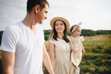 Aile, anne, baba, kız tarlada bir tepede yürüyorlar. Anne ve kızı aynı sarı elbiseli..