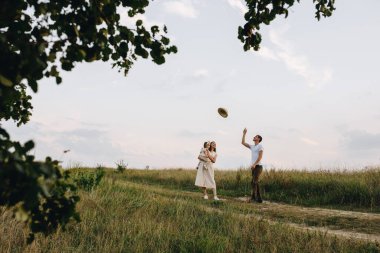 Aile, anne, baba, kız tarlada bir tepede yürüyorlar. Anne ve kızı aynı sarı elbiseli..