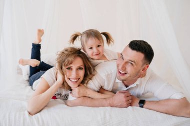 Sevimli kız ve baba gıdıklıyor anne evde birlikte oynayarak iyi vakit geçiriyor mutlu ebeveynler ve küçük kız çocuk eğlenceli aktivitelerin ve iletişimin tadını çıkarıyor aile gülüşleri rahatlatıcı