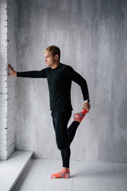 Evde idman yapıyorum. Eşofmanlı adam. Siyah spor üniforması. Erkek sporcu. Vücudu şişmiş. Triatlon. Sabah sporu. Vücut için bir takım egzersizler.