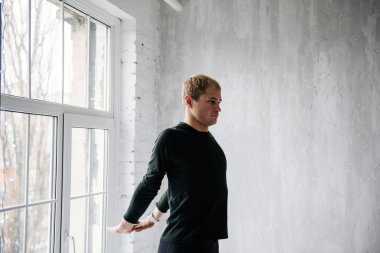 Evde idman yapıyorum. Eşofmanlı adam. Siyah spor üniforması. Erkek sporcu. Vücudu şişmiş. Triatlon. Sabah sporu. Vücut için bir takım egzersizler.