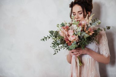 Gelin sabah şeffaf bir sabahlıkla toplanıyor. Pembeli çok güzel bir düğün buketi. Desenli duvar