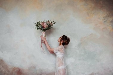 Gelin sabah şeffaf bir sabahlıkla toplanıyor. Pembeli çok güzel bir düğün buketi. Desenli duvar